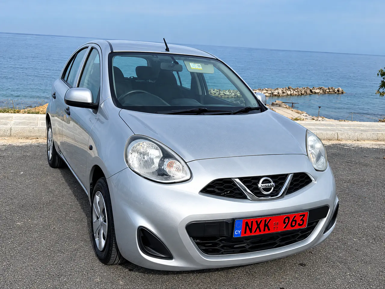 A silver Nissan Micra from the Nippy Turtle fleet parked by the sea